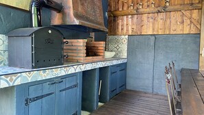 Une cuisine rustique avec un four en briques, des armoires en bois et un mur recouvert de carreaux.