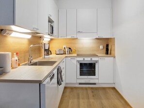 A compact kitchen with white cabinets, a built-in oven, a coffee maker, and a toaster. - Hovikatti by Interhome (Sotkamo)