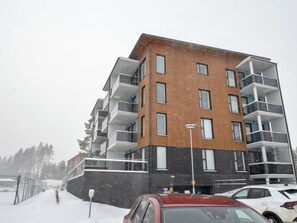 A multi-story residential building with balconies, a brick facade, and a parking area with cars. - Hovikatti by Interhome (Sotkamo)