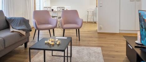 A modern living room with a sofa, two armchairs, a coffee table, and a TV.
