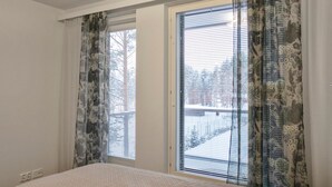 A bedroom with a bed, two pillows, a window with blinds, and curtains.