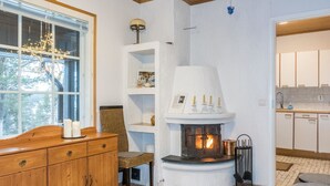 A cozy room with a fireplace, wooden furniture, and a view of the outdoors. - Torvokoski by Interhome (Utsjoki)