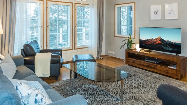 A modern living room with a glass coffee table, leather sofa, and a flat-screen TV on a wooden stand. - Torvokoski by Interhome (Utsjoki)