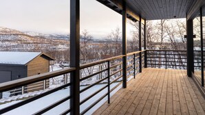 A wooden deck with a metal railing overlooking a snowy landscape. - Saanan lumous by Interhome (Enontekiö)