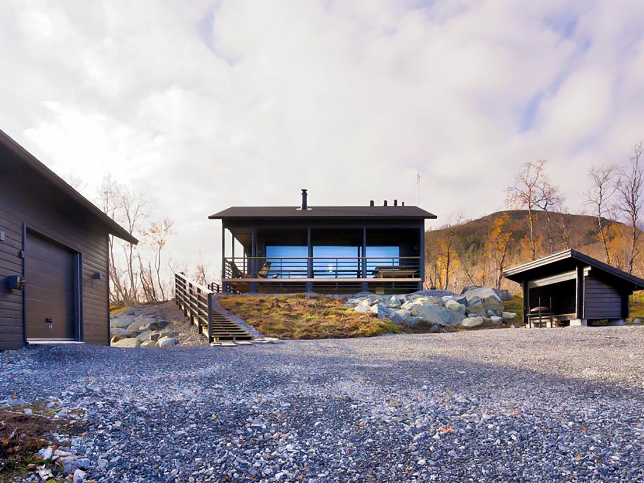 A modern house with a large windowed porch, a garage, and a small shed.