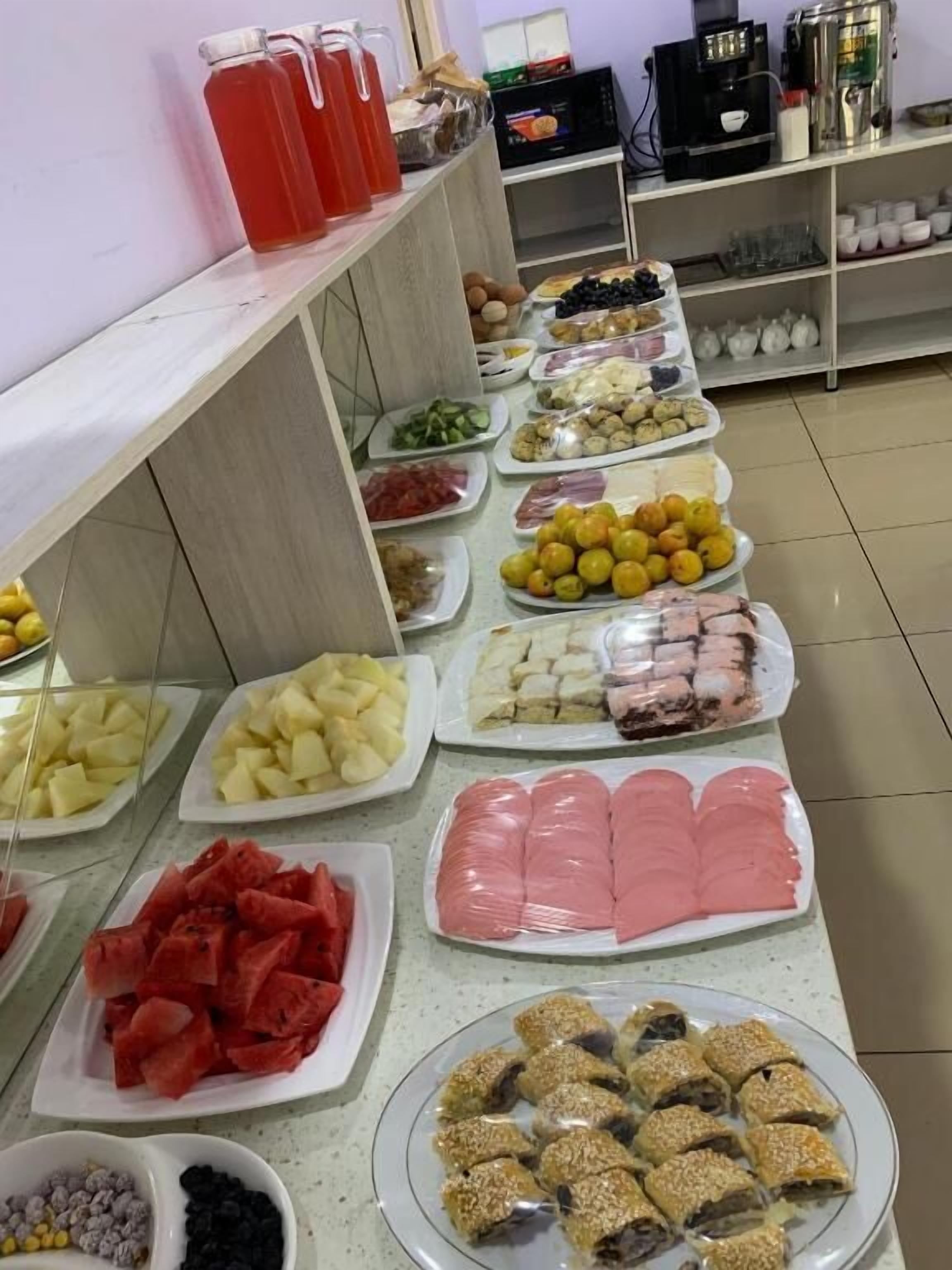 Un buffet proposant une variété de plats, notamment des fruits, des viandes et des pâtisseries.
