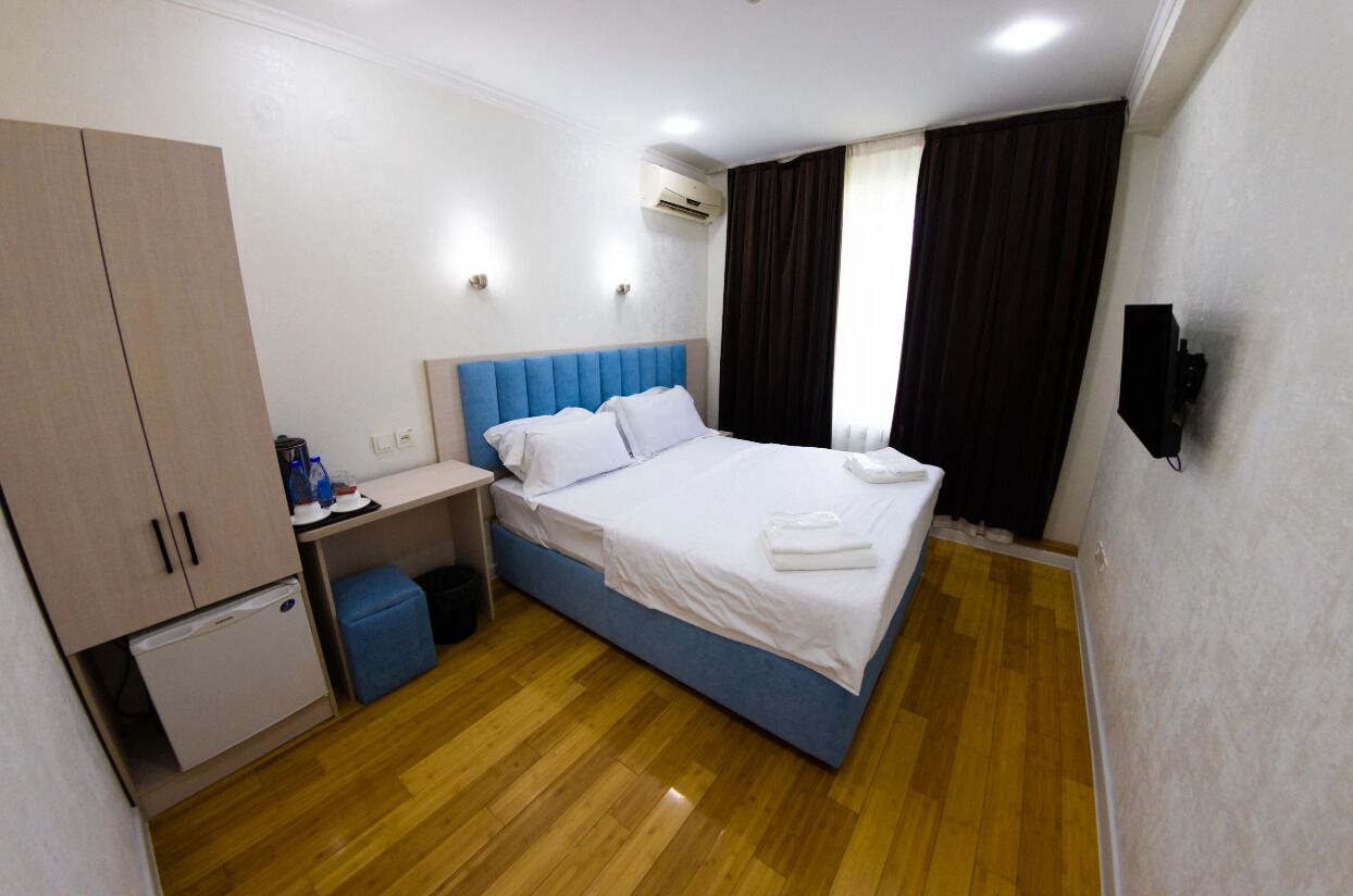 Une chambre d’hôtel équipée d’un lit, d’un bureau, d’une armoire et d’un petit réfrigérateur.