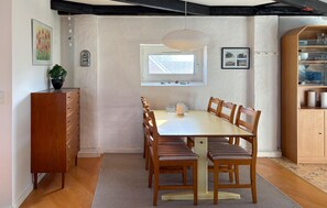 Un coin repas avec une table et des chaises en bois, une fenêtre et un meuble avec des portes en verre.