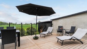 An outdoor patio with wicker chairs, a table, and a large umbrella. - Lovely home in Fejø with WiFi (Fejø)