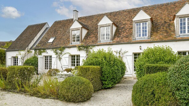 A traditional white building with a tiled roof and multiple windows, surrounded by well-maintained hedges and a gravel path. - Lovely home in Yèvre-la-Ville (Yèvre-la-Ville)