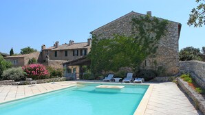 A swimming pool with lounge chairs and a stone building in the background.