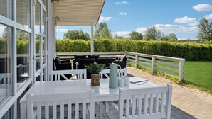 Eine Terrasse im Freien mit weißen Holzmöbeln, einem Tisch und Stühlen.