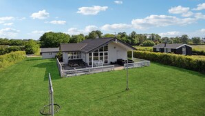 Einbungalow mit geneigtem Dach, großen Fenstern und einem eingezäunten Patio.