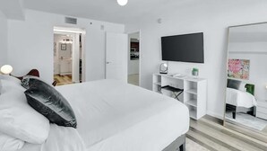 Une chambre moderne avec un grand lit, un téléviseur à écran plat, une armoire et un miroir.
