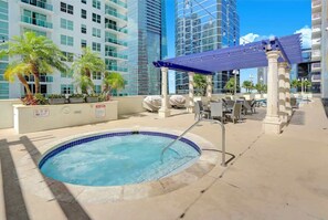 A rooftop pool area with a hot tub, lounge chairs, and a pergola.