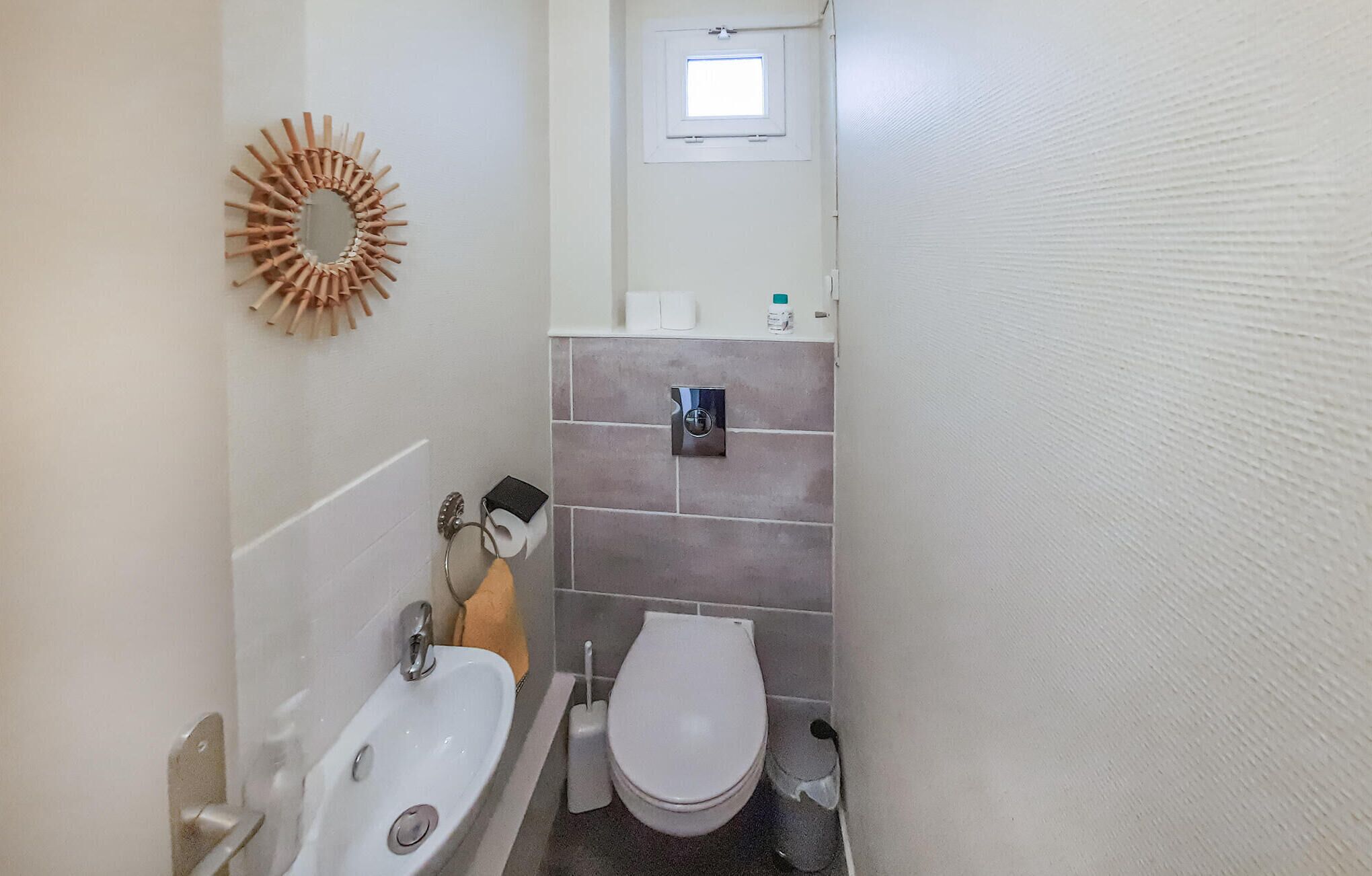 Ein kleines Badezimmer mit Waschbecken, Toilette und einem Fenster über der Toilette.