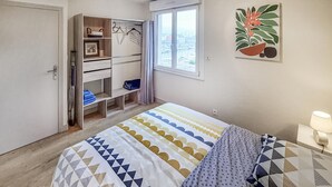A bedroom with a bed, a wardrobe, a window, and a painting. - Nice apartment in Redon with WiFi (Redon)