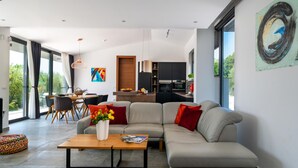 A modern living room with a sectional sofa, a coffee table, and a dining area with chairs and a table. - Awesome home in Rakalj (Rakalj)