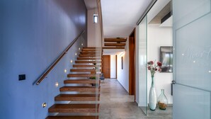 A modern staircase with wooden steps and glass railings, leading to a room with a glass door and a vase of flowers. - Awesome home in Rakalj (Rakalj)