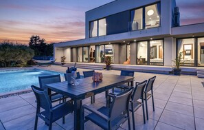 A modern house with a swimming pool, outdoor seating, and large windows. - Awesome home in Rakalj (Rakalj)