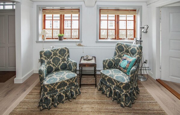 Ein Zimmer mit zwei gemusterten Sesseln, einem kleinen Tisch und einer Heizung.