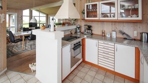 Een moderne keuken met witte kasten, een centraal eiland en een eethoek met tafel en stoelen.