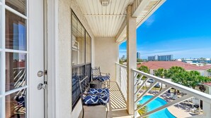 Een balkon met uitzicht op een zwembad en omliggende gebouwen.