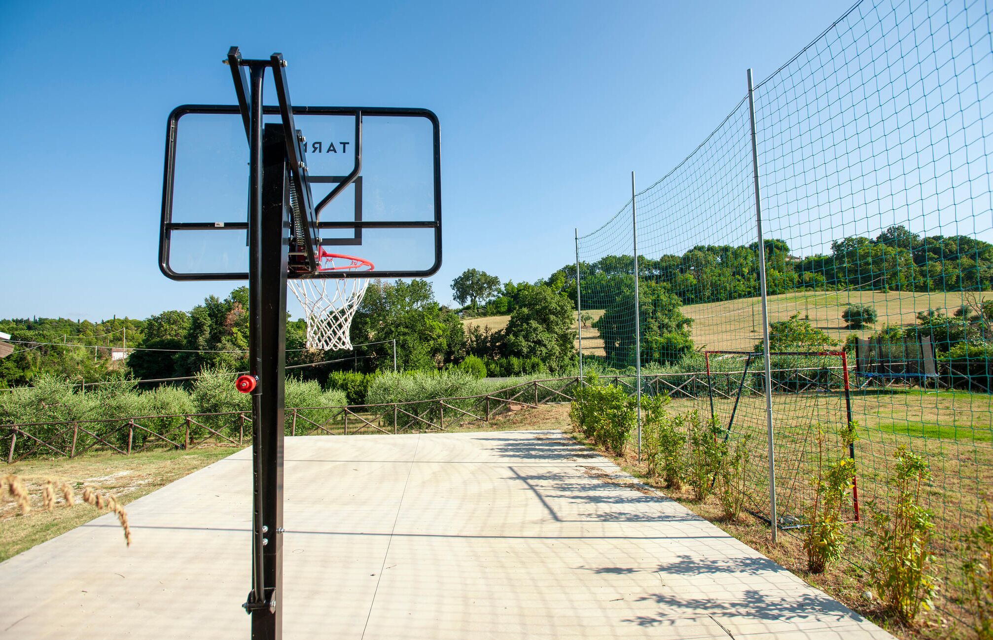 Un terrain de basket avec un panier, un filet et un ciel dégagé.