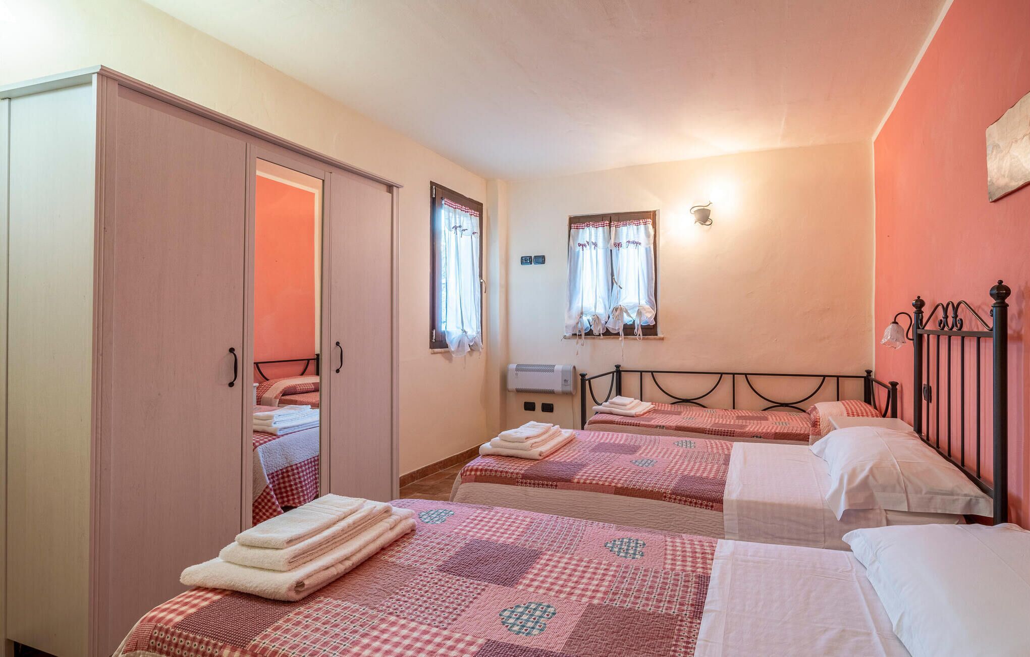 Habitación de hotel con dos camas, un armario, un calentador y una ventana con cortinas.