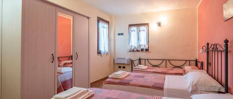 Habitación de hotel con dos camas, un armario, un calentador y una ventana con cortinas.
