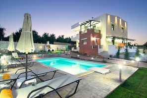 A modern two-story house with a swimming pool, outdoor seating, and a well-lit patio area. - Irene Villa, Peaceful Ambience (Panormos, Rethymno)