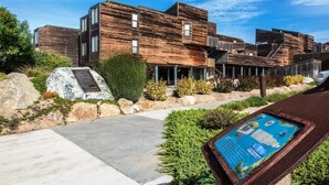 Un bâtiment moderne avec une façade en bois, un chemin pavé de pierres et une enseigne.