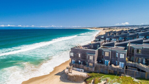 Un hôtel en bord de mer à l’architecture moderne, doté de nombreux balcons et offrant une vue sur la plage.