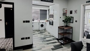A modern hotel lobby with a check-in counter, a coffee menu sign, a fire exit sign, and a view into the kitchen area. - Family Stay | Home from Home | Hot-Tub | Pets Free (BISPHAM)