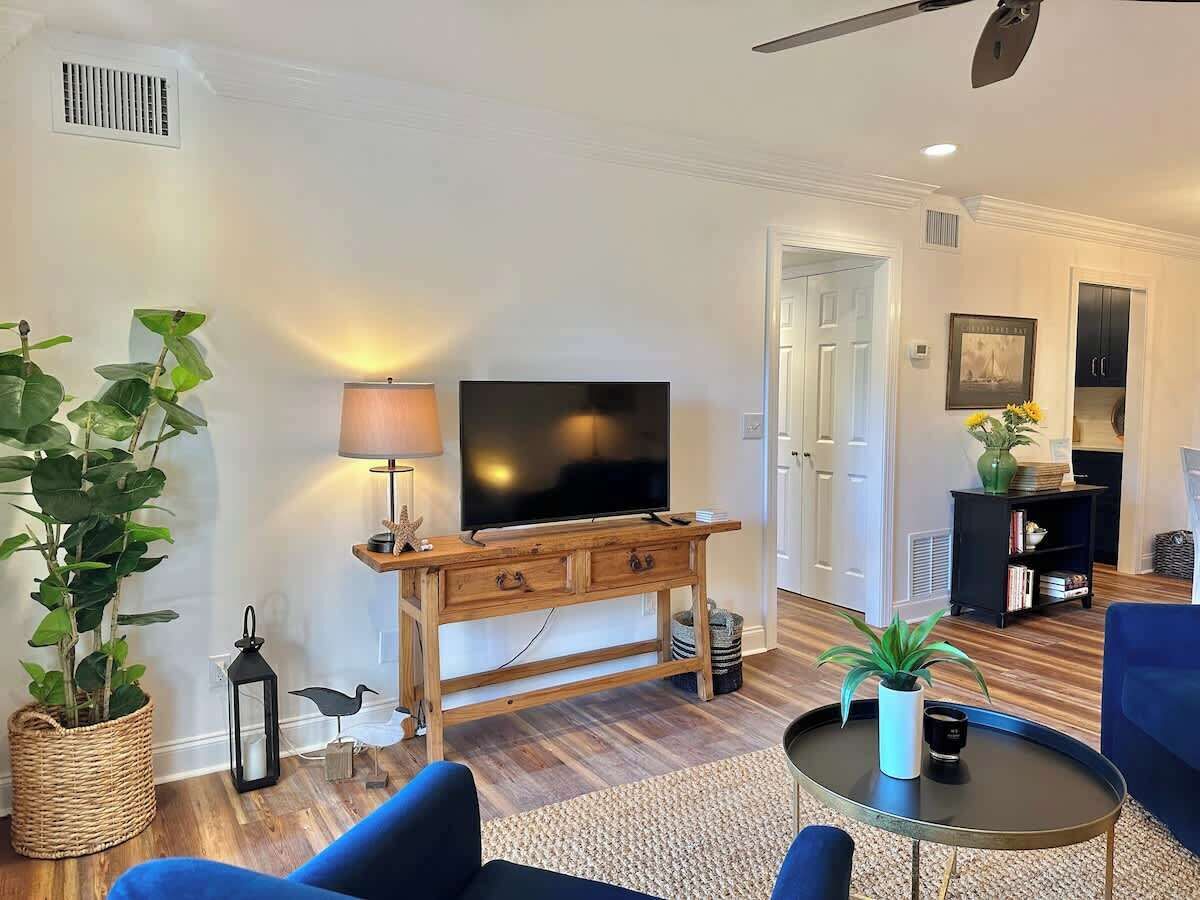 A living room with a television, wooden console, blue sofa, and a round coffee table.