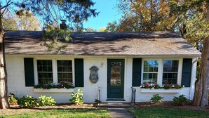 Una casa de un solo piso con puerta verde, fachada blanca y un pequeño porche.