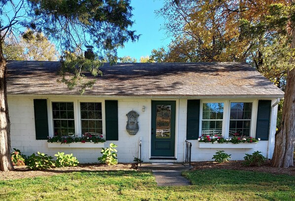 A single-story house with a green door, white exterior, and a small front porch.