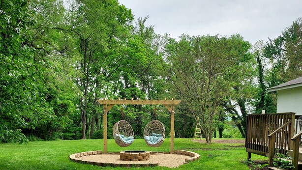 Un jardín con un columpio de madera y una zona de estar circular.