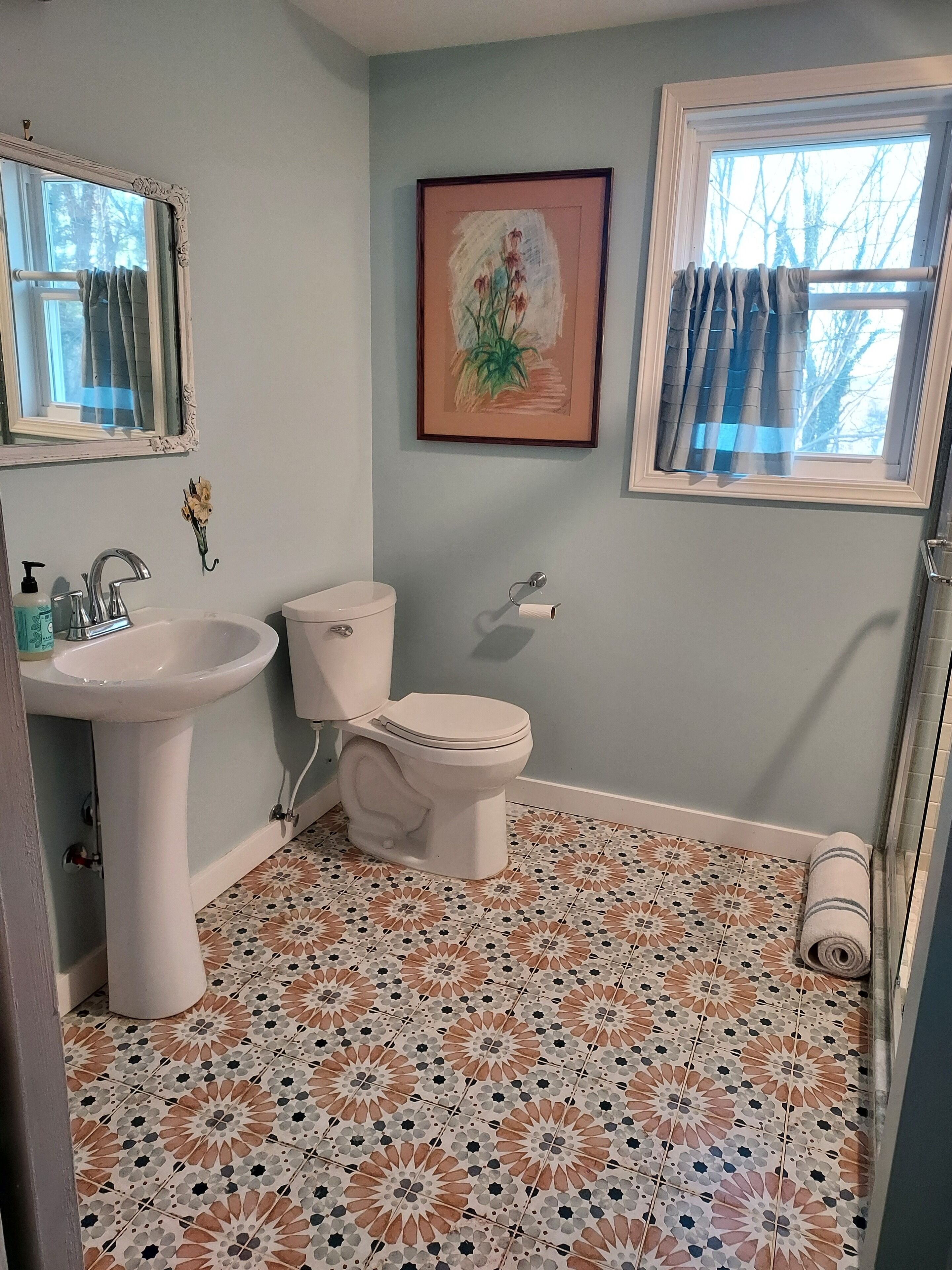 A bathroom with a sink, toilet, and a window with curtains.