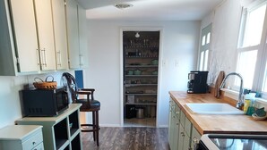 Una cocina con suelo de madera, armarios verdes, microondas, lavabo y ventana.
