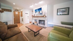 Ein Wohnzimmer mit Kamin, einer Couch, einem Couchtisch und einem grünen Sessel.