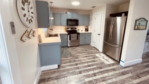 Une cuisine moderne avec des meubles gris, des appareils électroménagers en acier inoxydable et un plancher en bois.