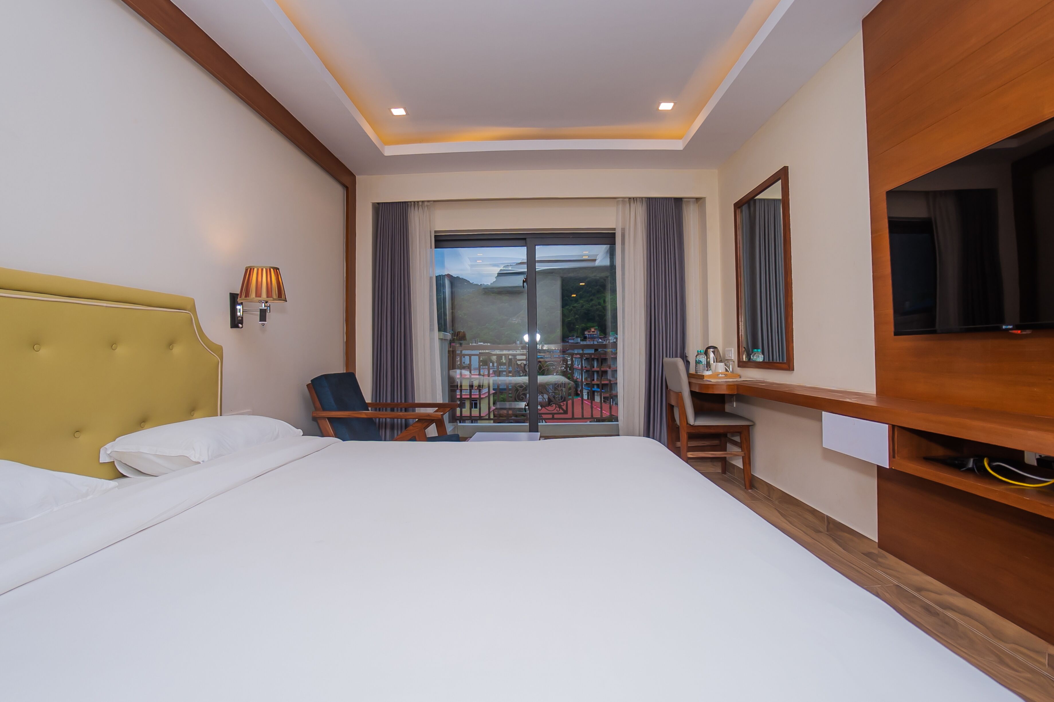 Une chambre d’hôtel avec un grand lit, un bureau, une chaise, une télévision et un balcon avec vue.