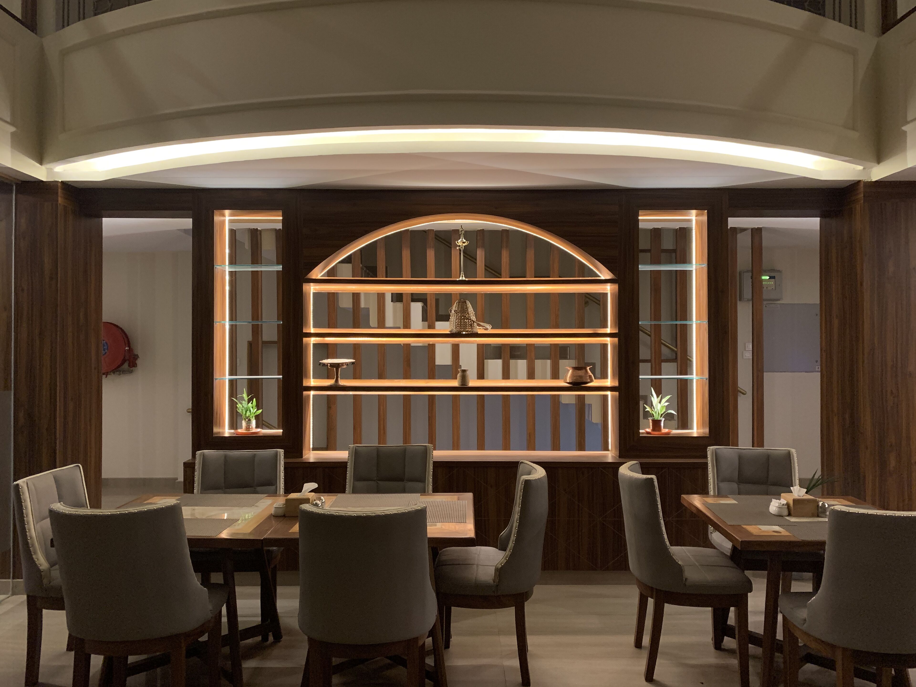 A dining area with a wooden table and chairs, a built-in shelf with decorative items, and a curved ceiling.