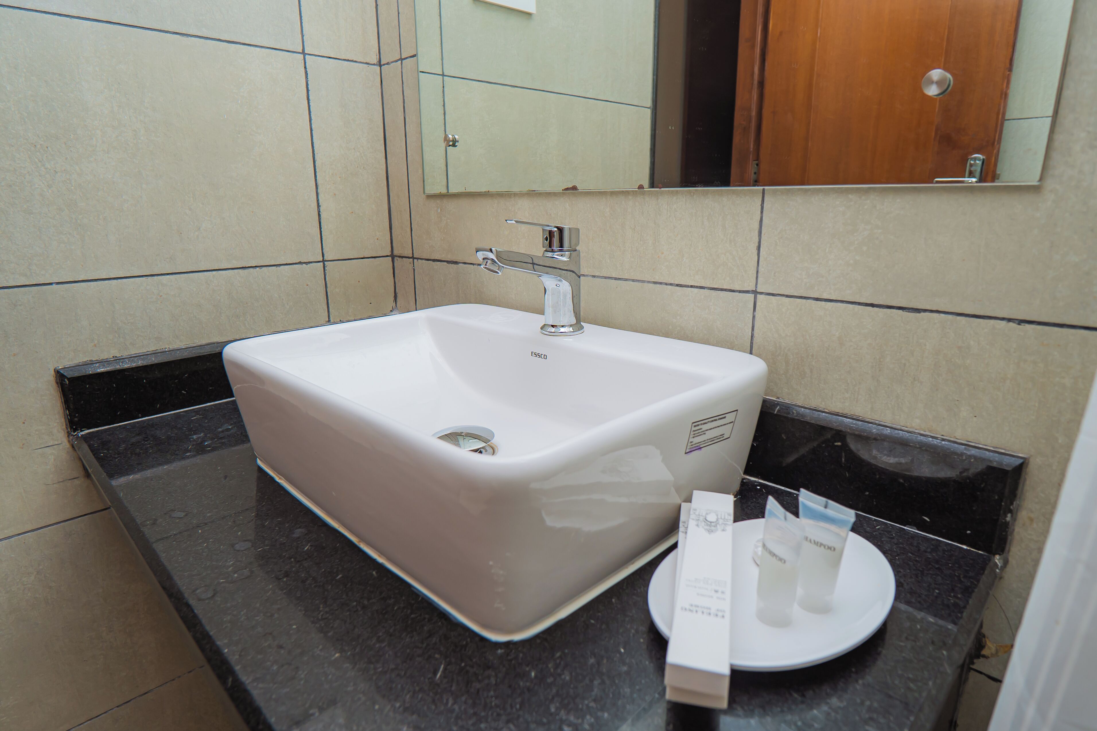 Een badkamer met een wit wastafelmeubel, een spiegel en toiletartikelen op het aanrecht.