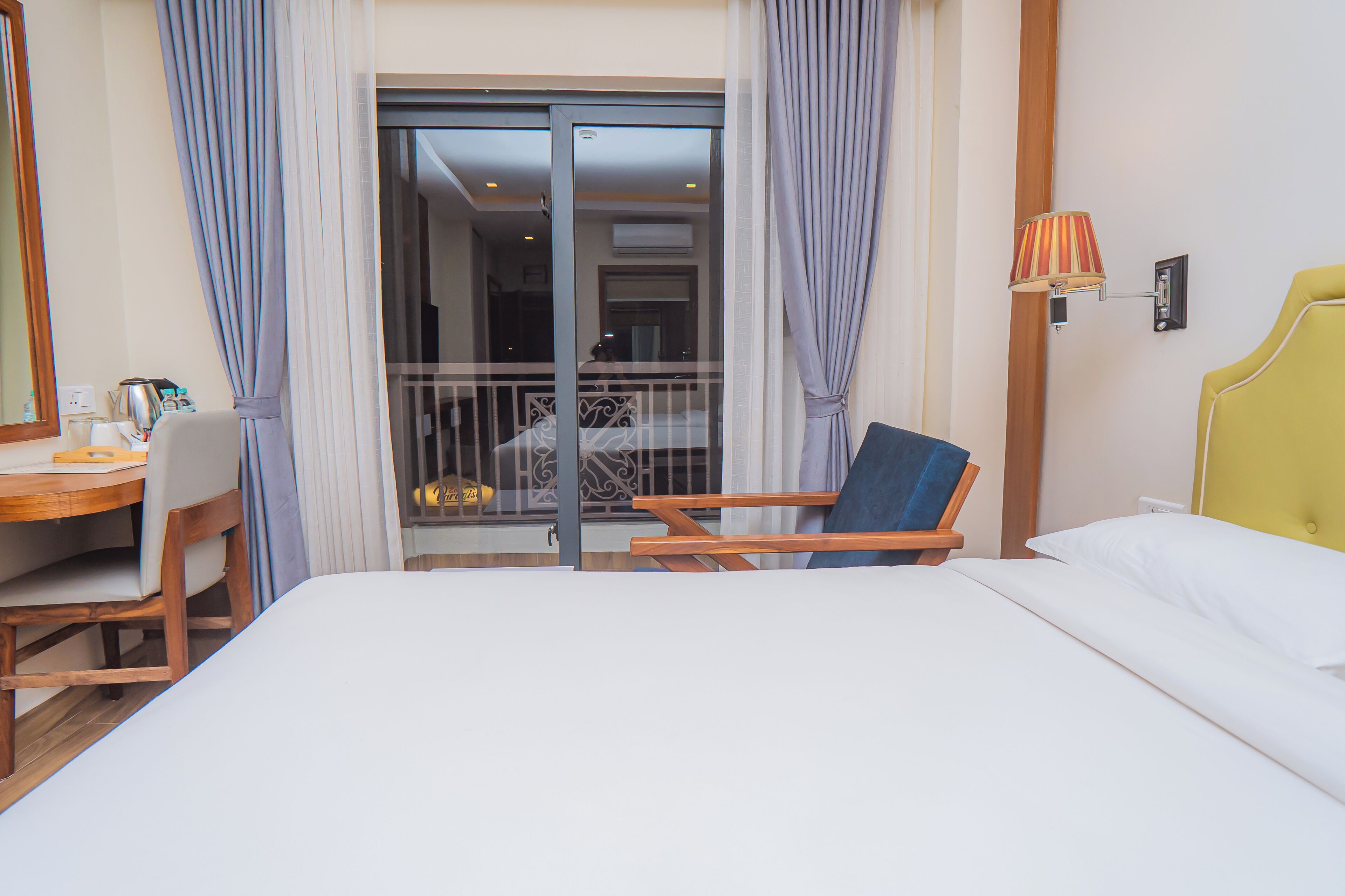 Una habitación de hotel con cama, escritorio, silla y balcón con barandilla.