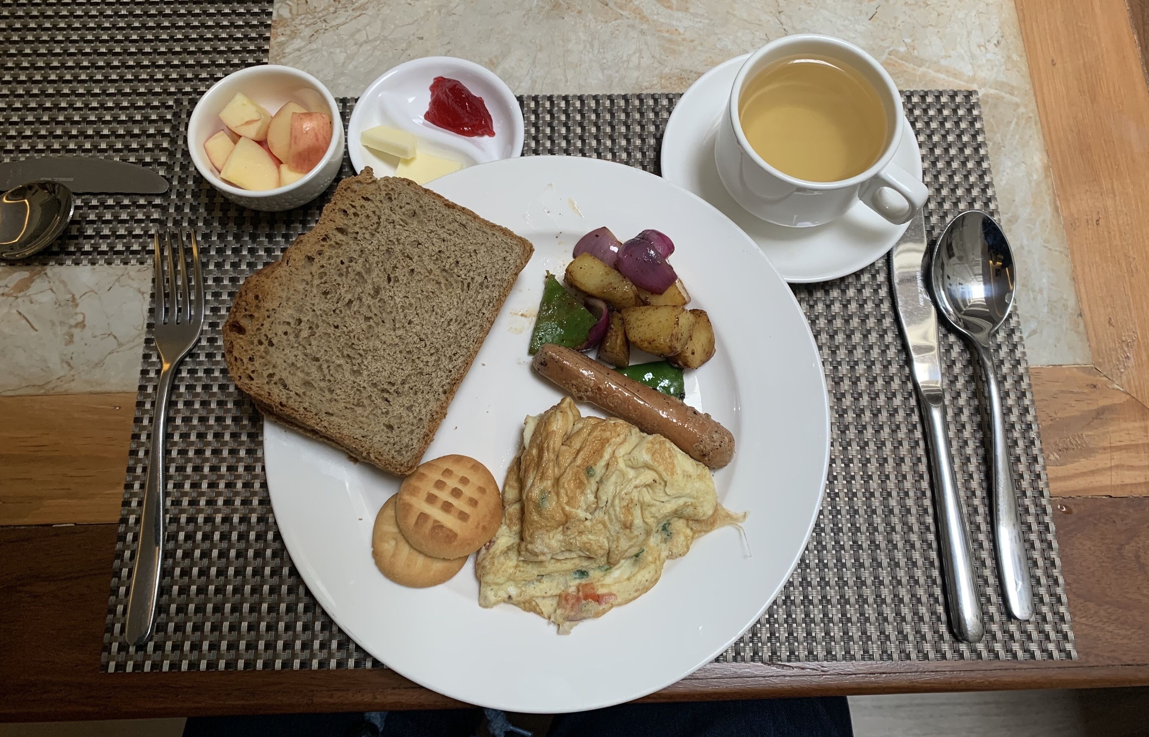A breakfast plate with toast, sausage, potatoes, and eggs, accompanied by a cup of coffee and condiments.