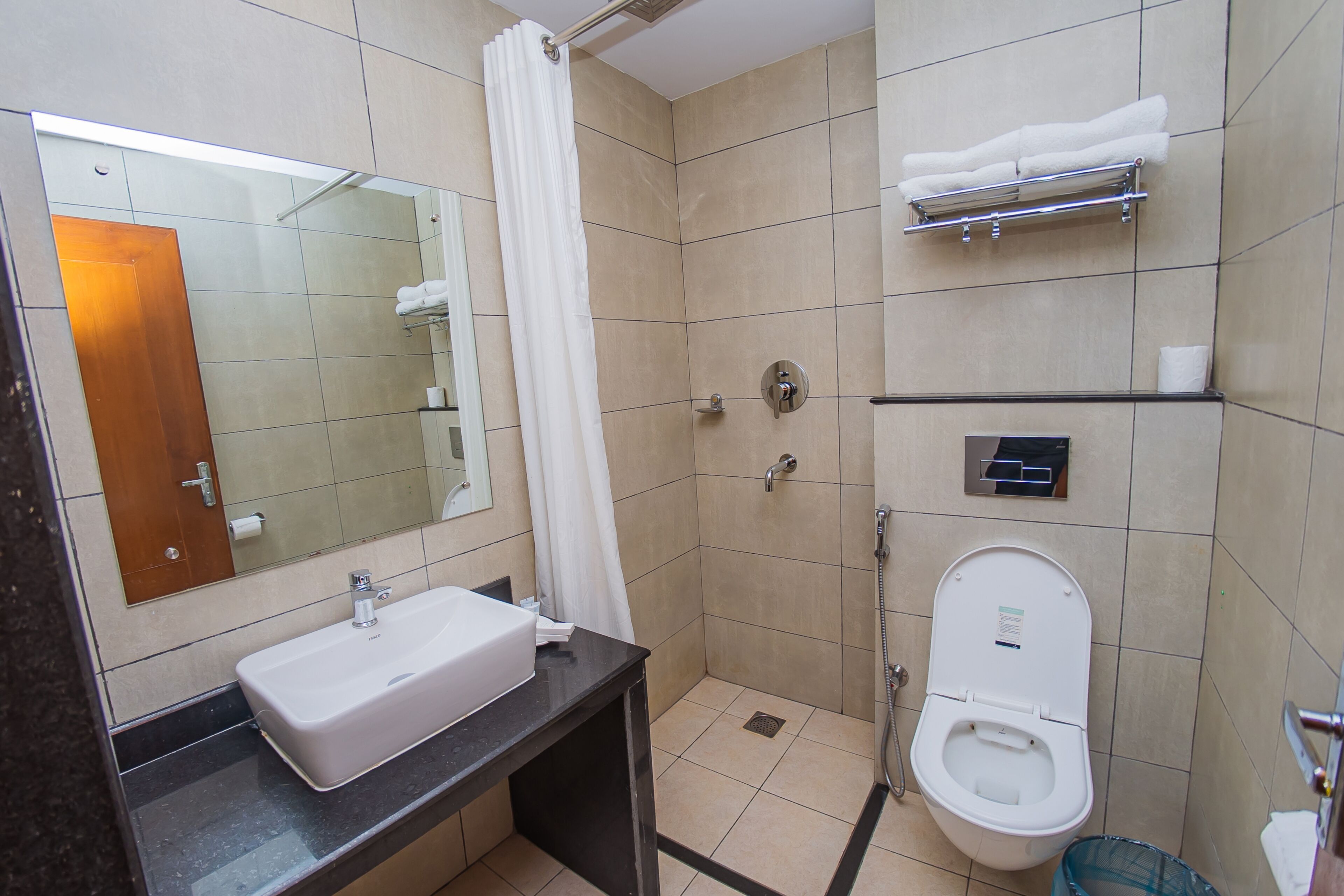 A bathroom with a sink, mirror, shower, toilet, and towel rack.