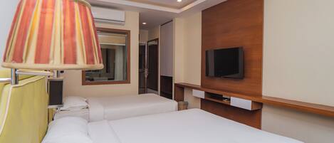 Una habitación de hotel con dos camas, televisión, lámpara y pared de paneles de madera.