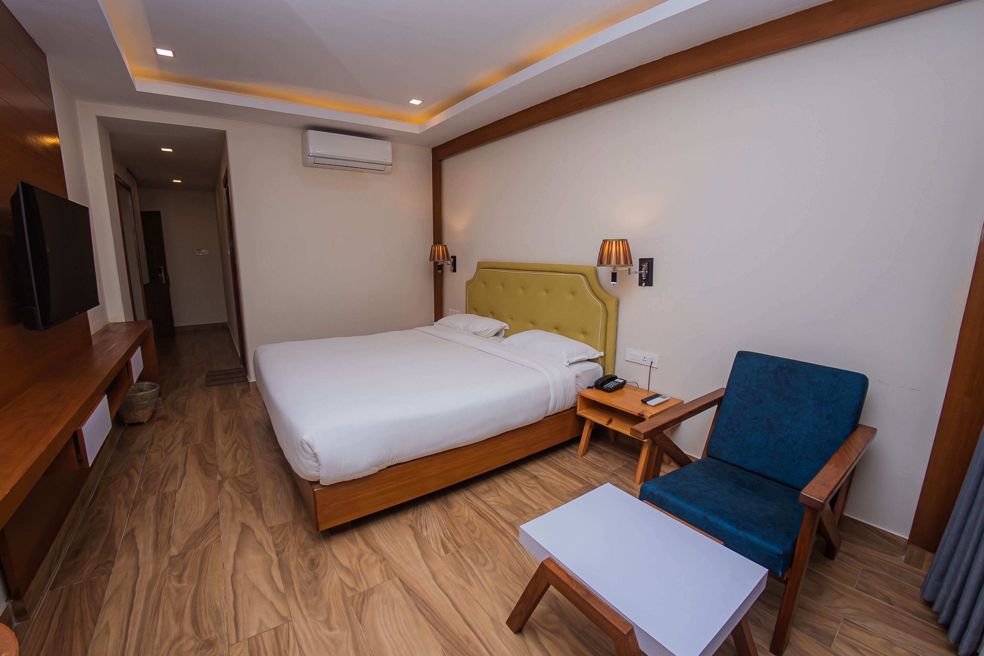 A hotel room with a bed, bedside table, chair, and a television.
